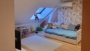 Une chambre de style « loft », avec un plafond en pente, une lucarne, un lit, un bureau et une chaise.
