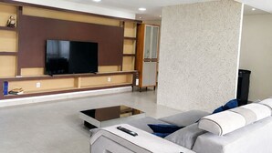 Un salon moderne doté d’un téléviseur à écran plat, d’un canapé, d’une table basse et d’étagères intégrées.