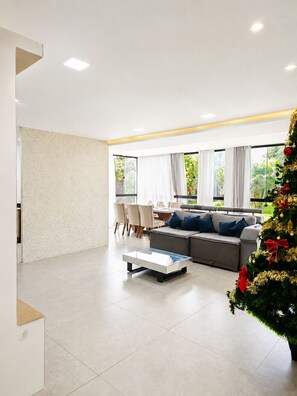 A modern living room with a sectional sofa, a coffee table, and a Christmas tree.