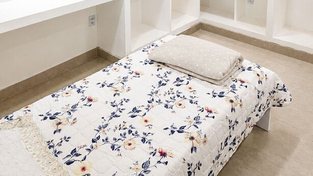 Une chambre à coucher avec un lit, une armoire et une petite table sur laquelle est posé un vase.