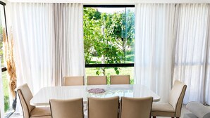 Un espace repas moderne avec une table en verre, des chaises de couleur beige et un canapé.
