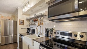Uma cozinha moderna com eletrodomésticos de aço inoxidável, painel de azulejos branco e piso de madeira.