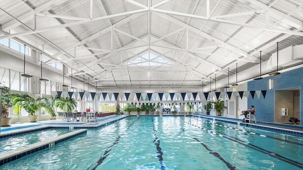 An indoor swimming pool with clear lanes, a high ceiling with a geometric pattern, and potted plants around the perimeter. - Bayside Resort: Great Location Walk to The Pool: (Selbyville)