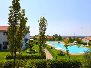 A residential area with a swimming pool, green lawns, and houses with red roofs. - SG Family - Abbey Home (Sandrà)