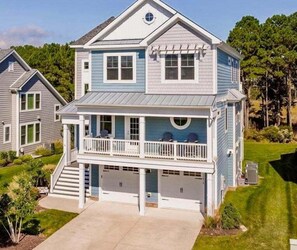 A two-story house with a front porch, a garage, and a landscaped yard.