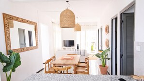 Eine moderne Küche mit Granit-Arbeitsplatte, einem Holzespeisetisch und Stühlen. Links befindet sich ein großer Spiegel, eine Hängeleuchte und ein Blumentopf.