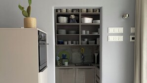 Une cuisine compacte dotée d’un meuble de rangement intégré, d’un réfrigérateur et d’une chaise.