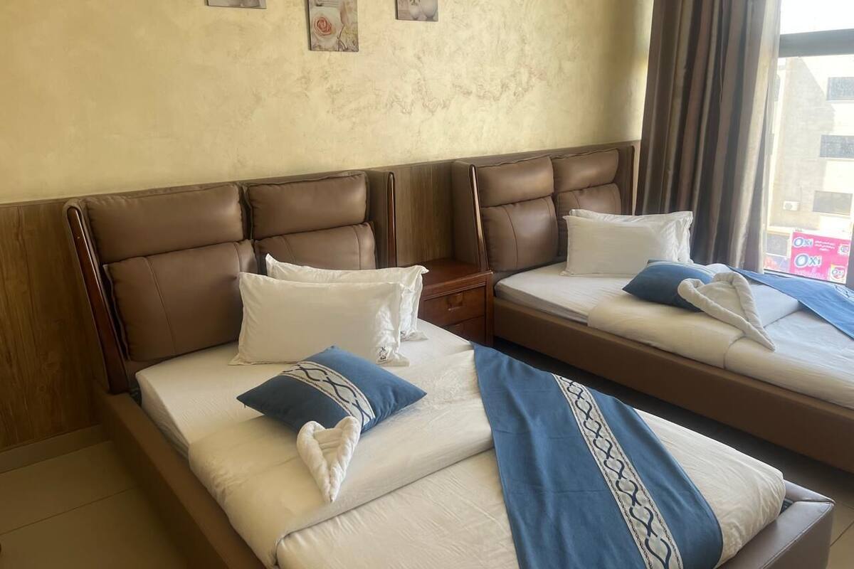 A hotel room with two beds, a wooden headboard, and artwork on the wall.