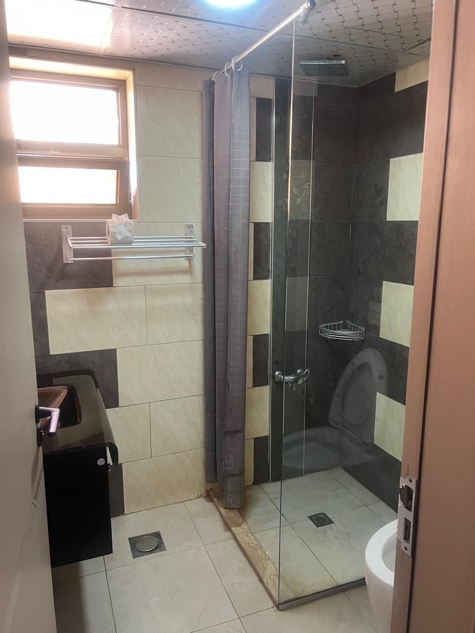 A bathroom with a glass shower enclosure, a toilet, and a sink.