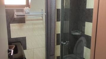 A bathroom with a glass shower enclosure, a toilet, and a sink.