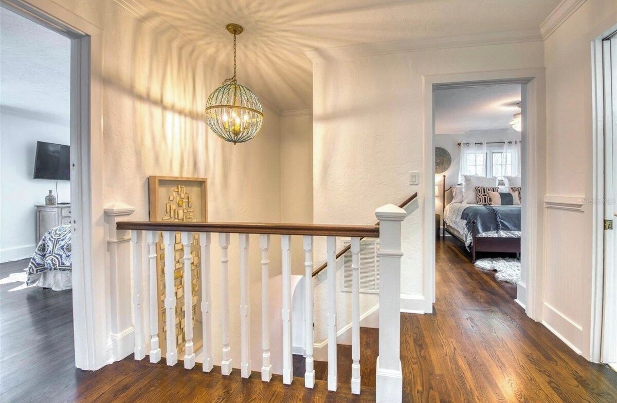 A staircase with a white balustrade leading to a bedroom with a bed and a window.