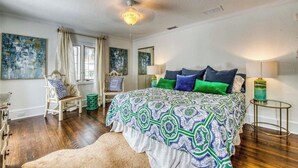Ein Schlafzimmer mit einem großen Bett, einem Sessel, einem kleinen Tisch und Bildern an den Wänden.