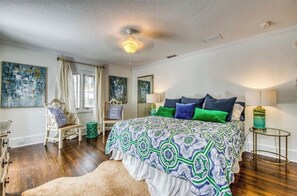 A bedroom with a large bed, a chair, a small table, and artwork on the walls. - Beautiful Historic Ringling house! (Sarasota)