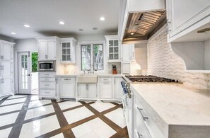 Une cuisine avec des meubles blancs, un îlot central, un four à micro-ondes et une cuisinière.