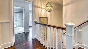 Ein Flur mit einer Holztreppe, weißen Geländern und einem Chandelier.