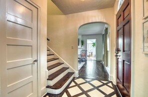 A hallway with a staircase, a door, and a patterned floor. - Beautiful Historic Ringling house! (Sarasota)