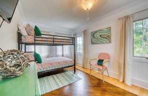 Une chambre avec un lit superposé, une chaise, un tapis et un tableau mural.