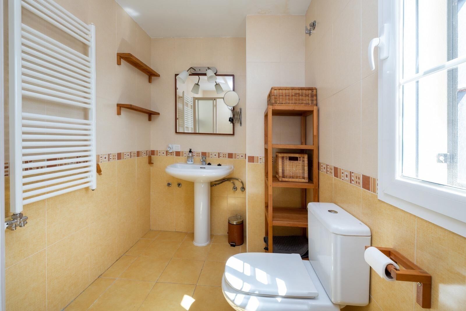 Une petite salle de bain avec des toilettes blanches, un lavabo, un miroir et une fenêtre.