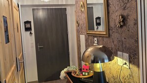 Ein Flur mit Holztür, einem Spiegel, einer Lampe und einem kleinen Tisch mit einer Dekoration.