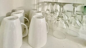 Une collection de tasses blanches et de verres à vin, disposés sur une étagère.