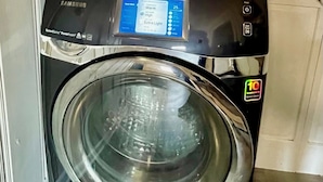 Une machine à laver à chargement frontal dotée d’un panneau de commande numérique et d’une porte en acier inoxydable.