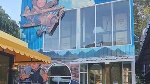 Een gebouw met een muurschildering van een man in een auto en een rond raam.