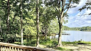 Eine Holzterrasse mit Blick auf einen See, Bäume und einen Steg.