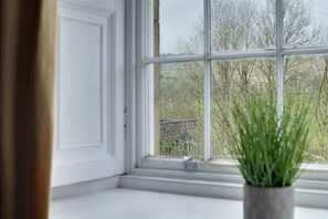 Una ventana con vista a un muro de ladrillo y árboles.