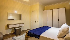Een slaapkamer met een bed, een kledingkast, een spiegel en een hanglamp.