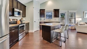 A modern kitchen with dark wood cabinets, stainless steel appliances, and a central island with bar stools. - Salt Air Cottage - Private Pool, Dog Friendly, 4 Blocks to Beach (Carolina Beach)