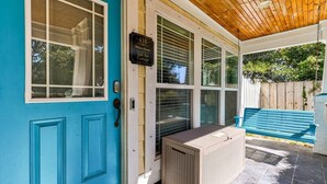 A covered porch with a blue door, a sign reading "Salt Air Cottage," and a beige air conditioning unit. - Salt Air Cottage - Private Pool, Dog Friendly, 4 Blocks to Beach (Carolina Beach)