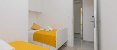 A hotel room with two beds, a wardrobe, and a bathroom visible through an open door.