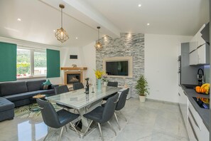 A modern kitchen with a dining area, a fireplace, and a large window. - Tranquil Country Villa in Naklice for 6 (Omis)