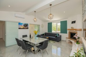 A modern living room with a glass dining table, black chairs, a grey sofa, and a fireplace. - Tranquil Country Villa in Naklice for 6 (Omis)
