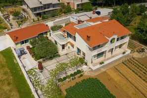 A two-story house with a red-tiled roof, a balcony, and a garden. - Tranquil Country Villa in Naklice for 6 (Omis)