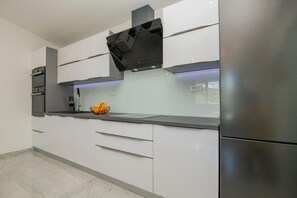 A modern kitchen with white cabinetry, a stainless steel refrigerator, and a black range hood. - Tranquil Country Villa in Naklice for 6 (Omis)