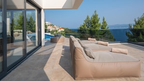 Ein moderner Außenbereich mit Pool, Sitzgelegenheiten und Meerblick.