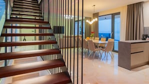 Ein modernes Interieur mit einer Treppe, einem Essbereich und Meerblick.