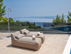 An outdoor seating area with a pool, a glass balustrade, and a view of the sea. - Luxury Seaview Villa With Jacuzzi for 10 (Imotski)