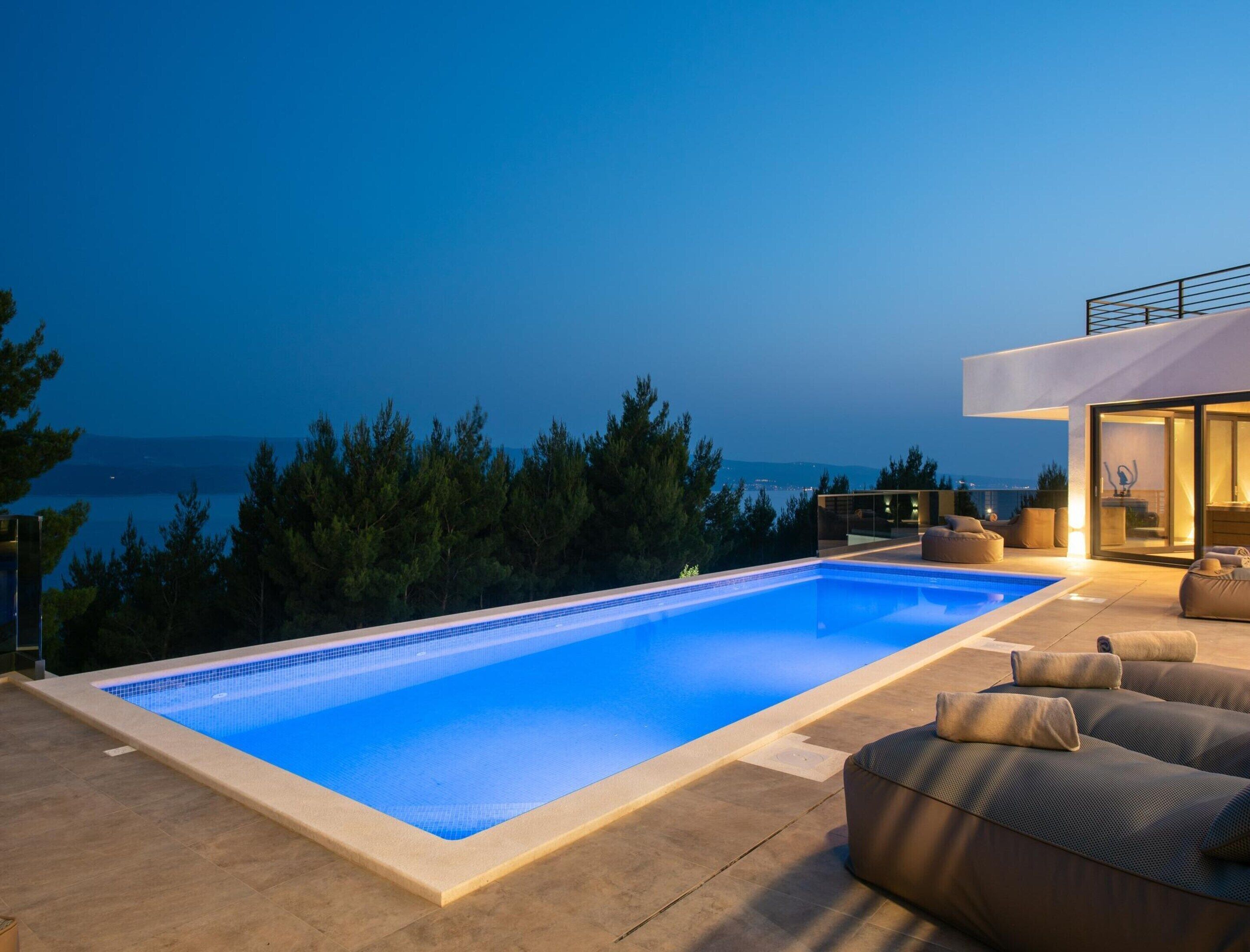 Une piscine avec vue sur la mer, un espace extérieur aménagé et un bâtiment moderne.