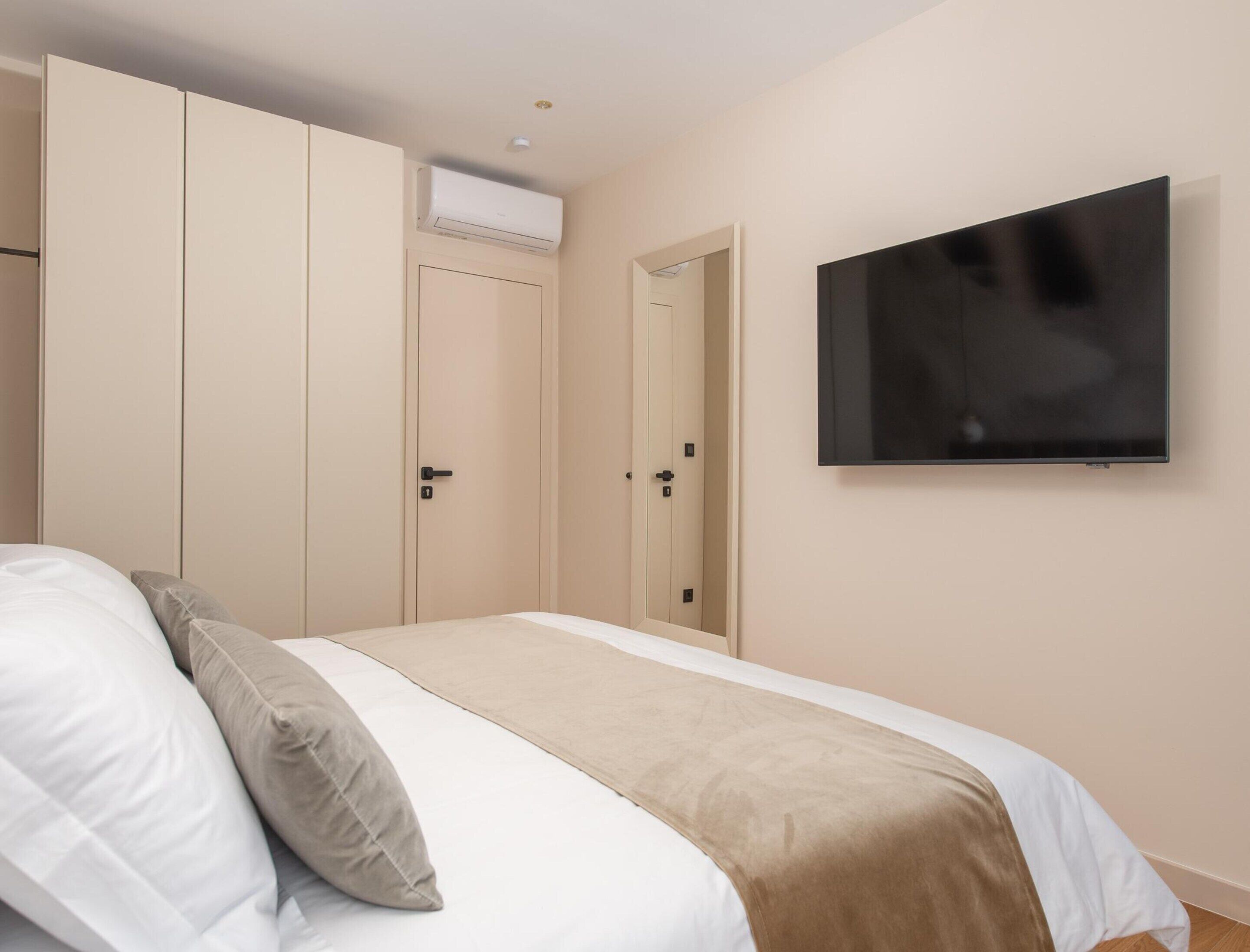 A bedroom with a bed, a television, and a wardrobe.
