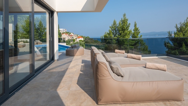 Ein moderner Außenbereich mit Pool, Sitzgelegenheit und Meerblick.