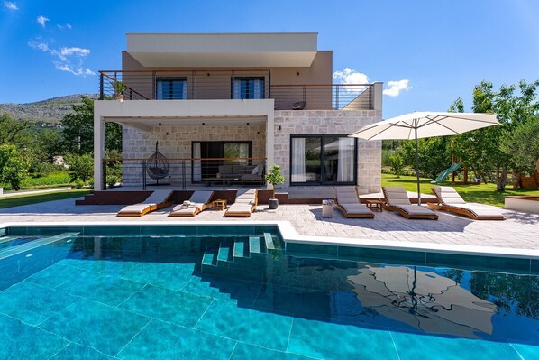 A modern two-story house with a swimming pool, outdoor seating, and a mountain backdrop. - Stylish 4-Bedroom Villa Agrosa with 30 m2 Private Pool, Hydromassage, Finnish Sauna and Fun zone (Srinjine)