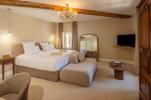 A bedroom with a large bed, a television, a mirror, and a chandelier. - Villa Roubia Hôtel & Spa (Roubia)