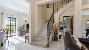 A spacious living area with a staircase, a dining area, and a sofa. - Quiet Hideaway with Heated Pool (Algoz)