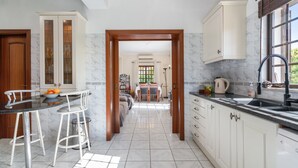 A modern kitchen with white cabinets, a marble countertop, and a dining area with a table and chairs. - Quiet Hideaway with Heated Pool (Algoz)