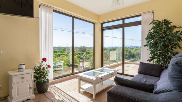 A living room with a sofa, a small table, a nightstand, and a potted plant. - Quiet Hideaway with Heated Pool (Algoz)