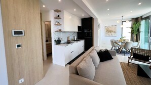 A modern apartment with a kitchenette, a sofa, a dining area, and a large window. - Omis Seaside Retreat for Family (Imotski)