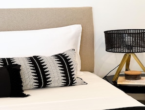 A bed with a white pillow and a black and white patterned pillow, a beige headboard, and a black lamp with a gold base on a side table. - Omis Seaside Retreat for Family (Imotski)