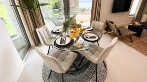 A dining area with a glass table, chairs, and a view of the outdoors. - Omis Seaside Retreat for Family (Imotski)